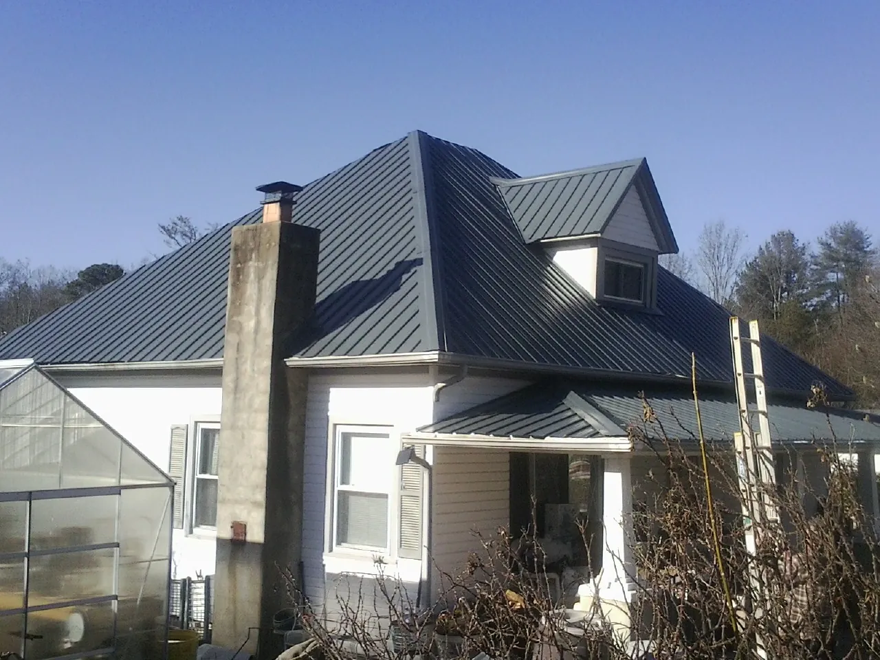 Dark blue standing seam metal roof on a white farmhouse with dormer in Ocean Park
