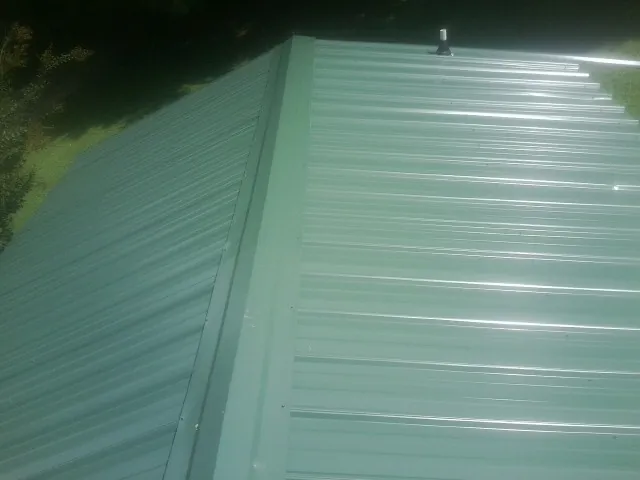 New green metal panels meeting at the ridge of a roof — Flat Roof Repair work by our crew in Ocean Park