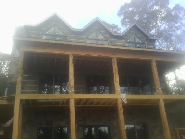 Dormers and porch framing on a large log home under construction — Roof Coating work by our crew in Ocean Park