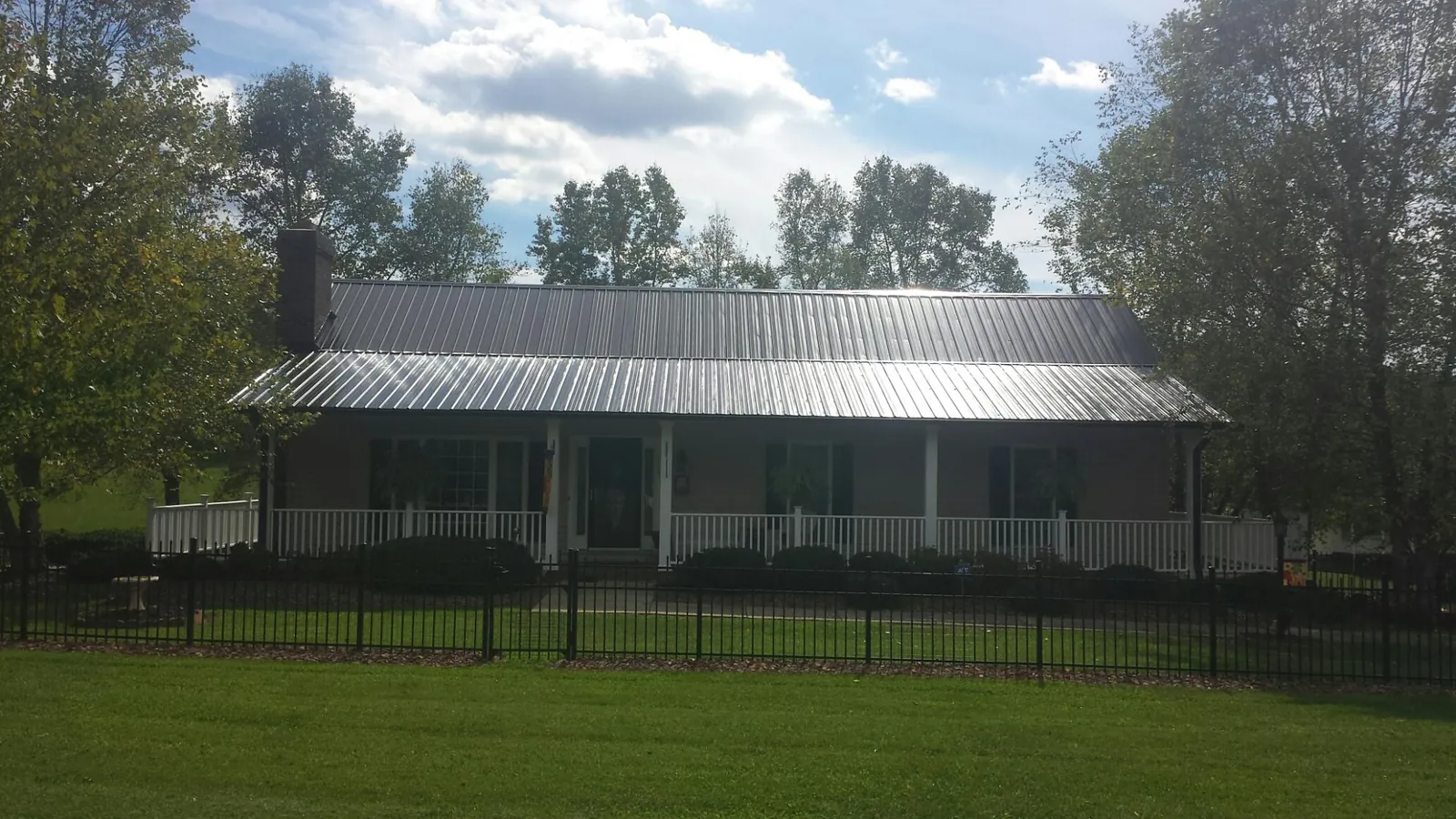 Gray metal roof on a brick ranch with a full width front porch — Gutter Guard Installation work by our crew in Ocean Park