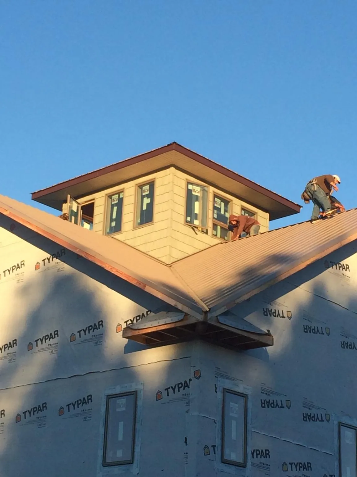 Roofers working around a rooftop cupola on a new metal roof at sunset — Roof Waterproofing in Ocean Park by Roofing Brothers